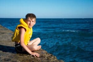 Autistic child practicing safety skills and wearing a life jacket.